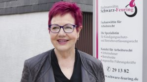 Christel Karin Schwarz-Feuring vor dem Kanzleischild. Frau Schwarz-Feuring steht vor Ihrem Kanzleischild.